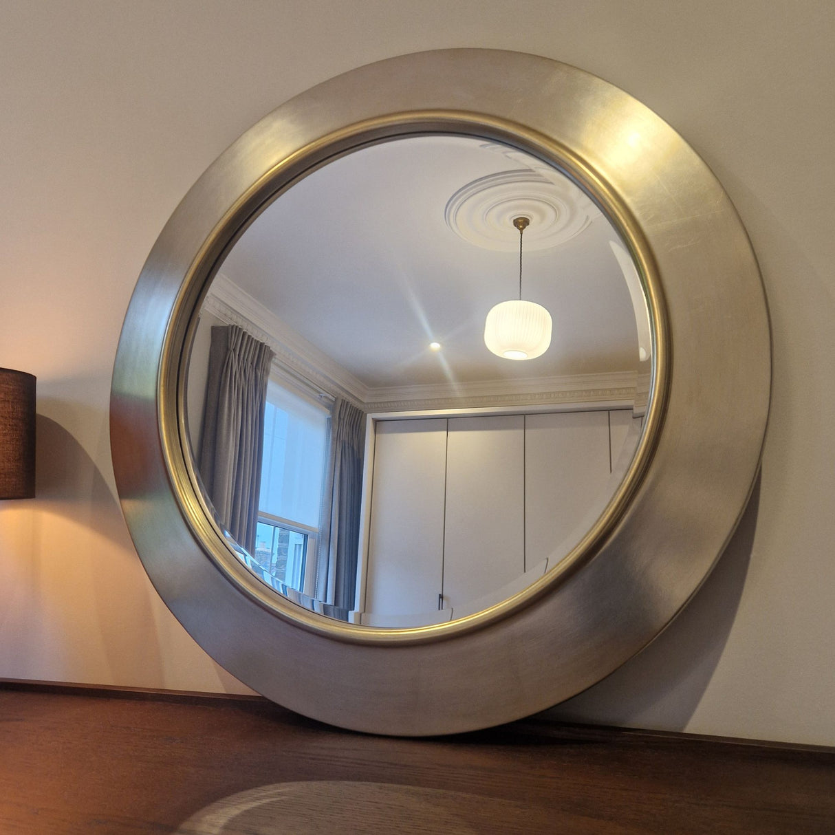 Round metallic mirror on a wall with a room reflection
