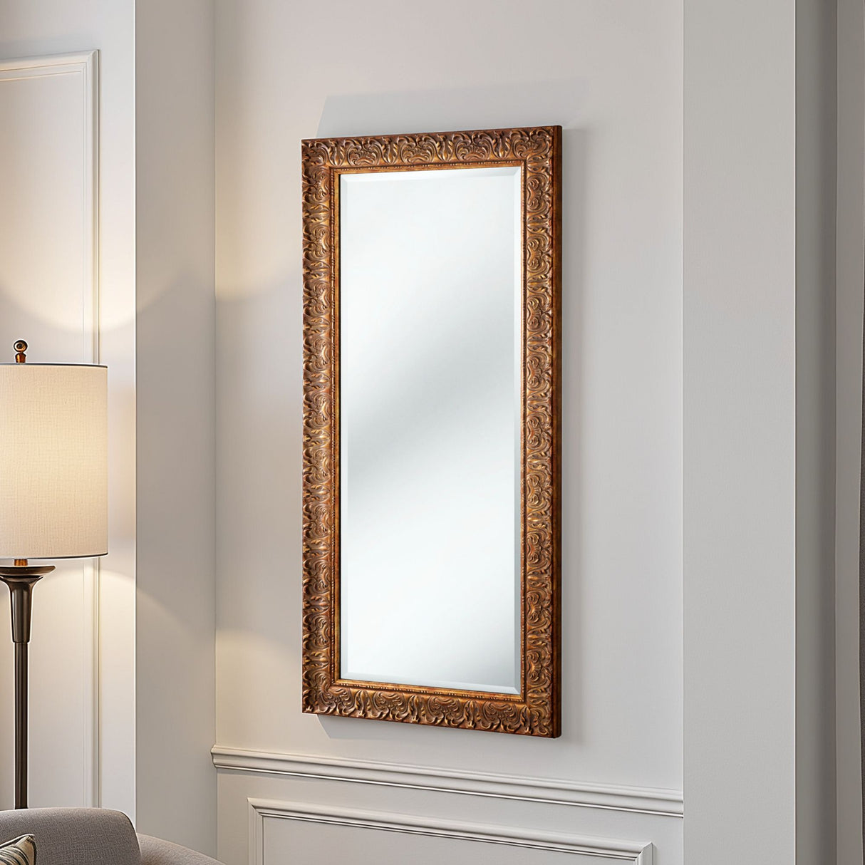 Decorative wall mirror with ornate gold frame on a light gray wall.