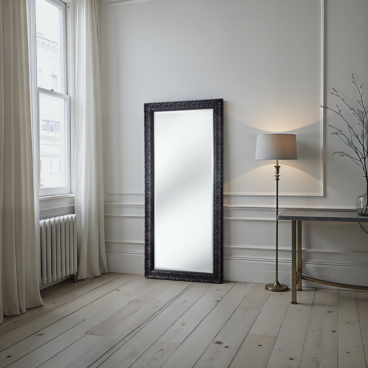 Modern interior with a large mirror, lamp, and table against a white wall.