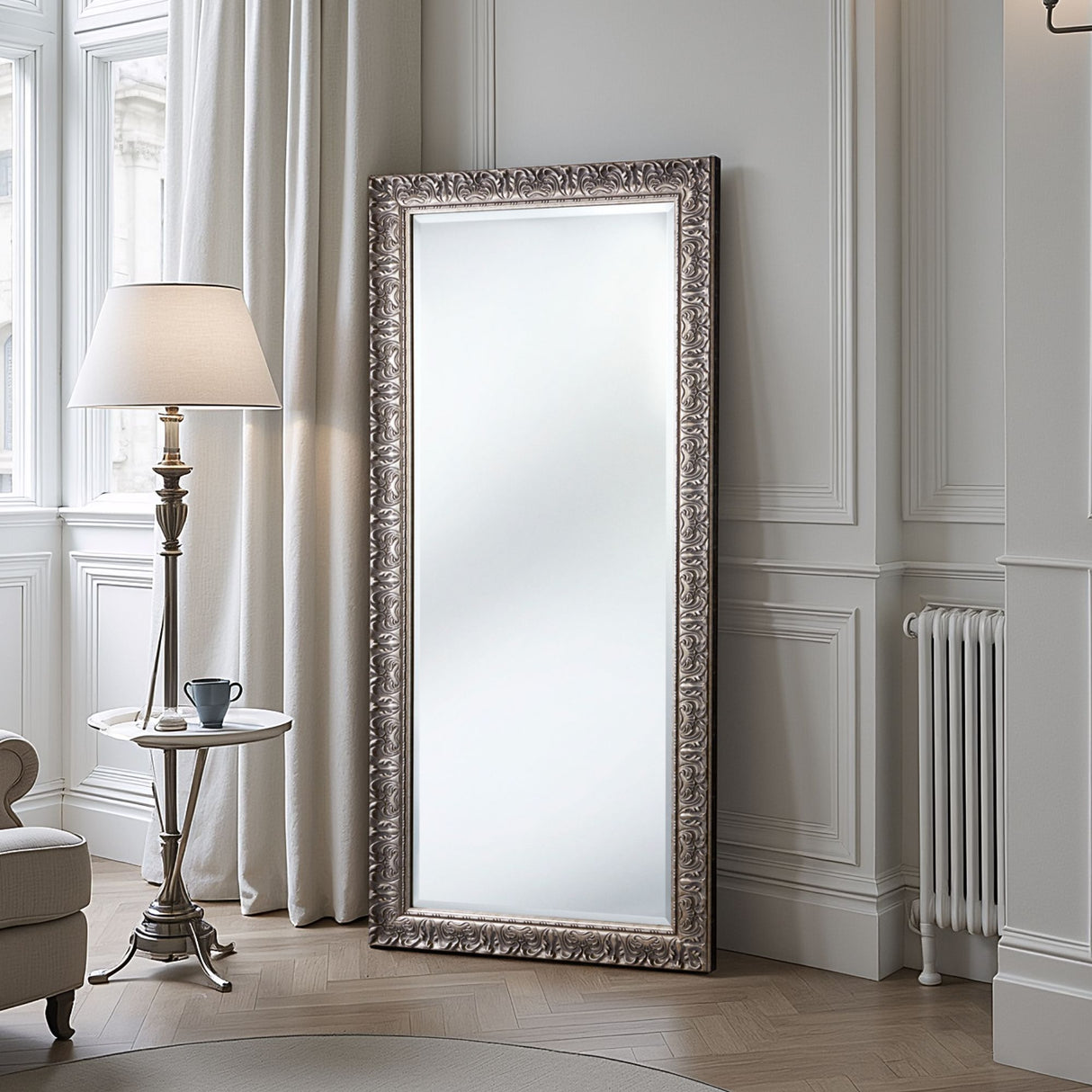 Decorative floor mirror with ornate frame in a room with a lamp and table.