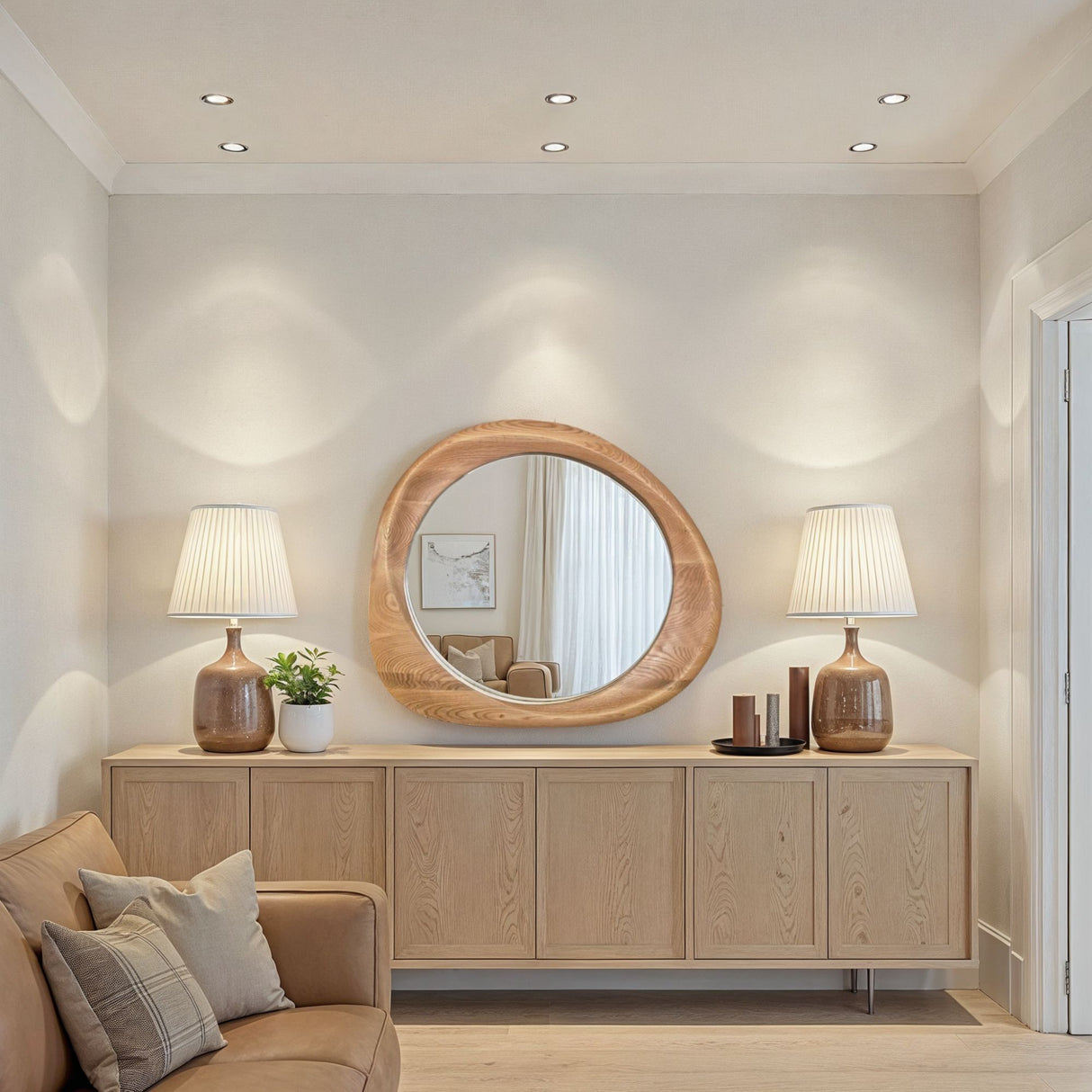Modern living room with wooden sideboard, round mirror, and beige sofa.