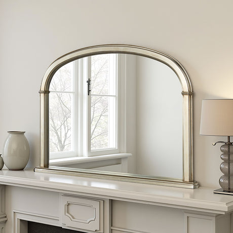 Decorative mirror with silver frame on a white wall above a fireplace.