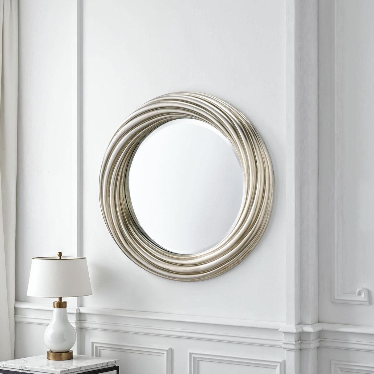 Decorative round mirror with a textured frame on a white wall with molding.