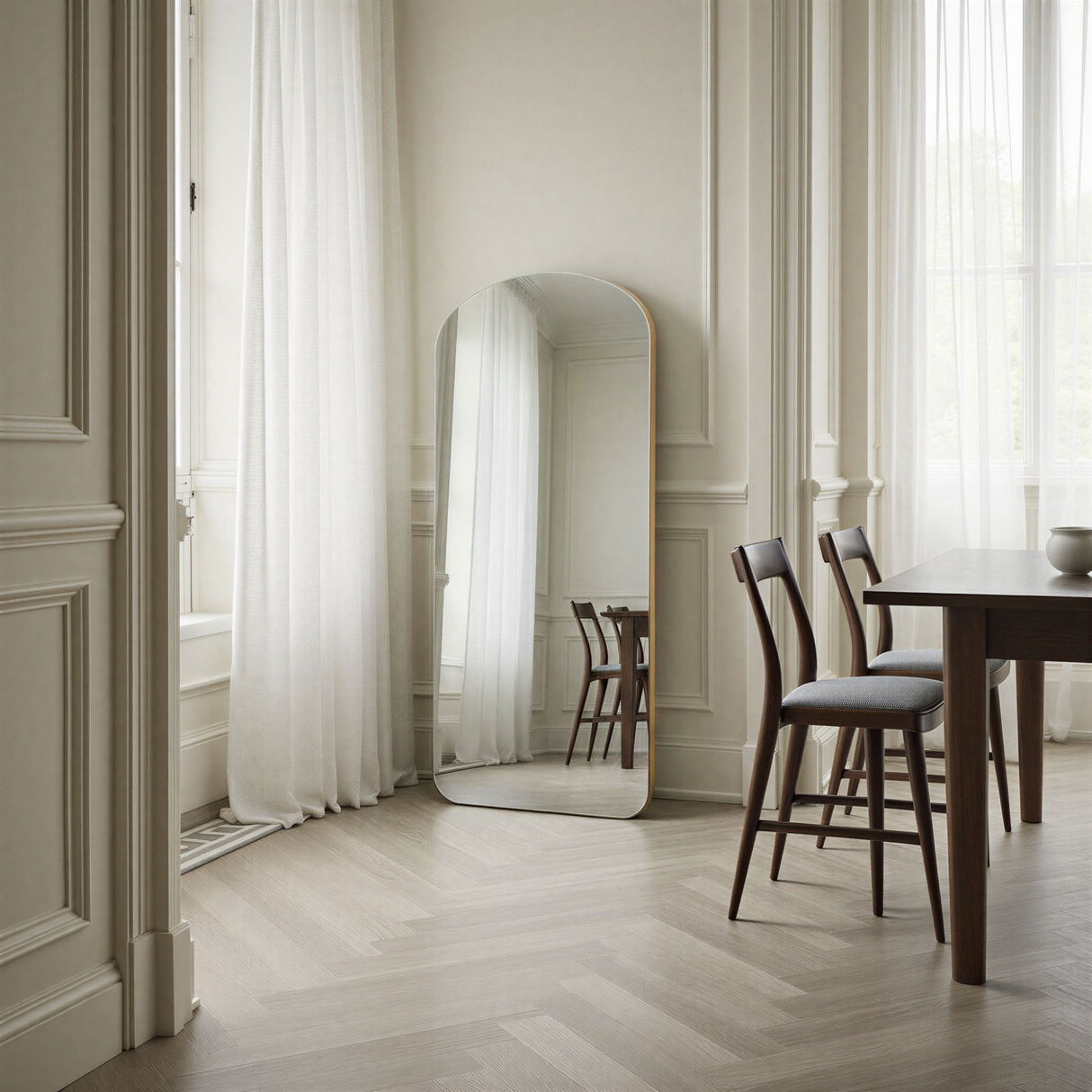 Dining room with a large mirror on the wall, wooden table, and chairs.