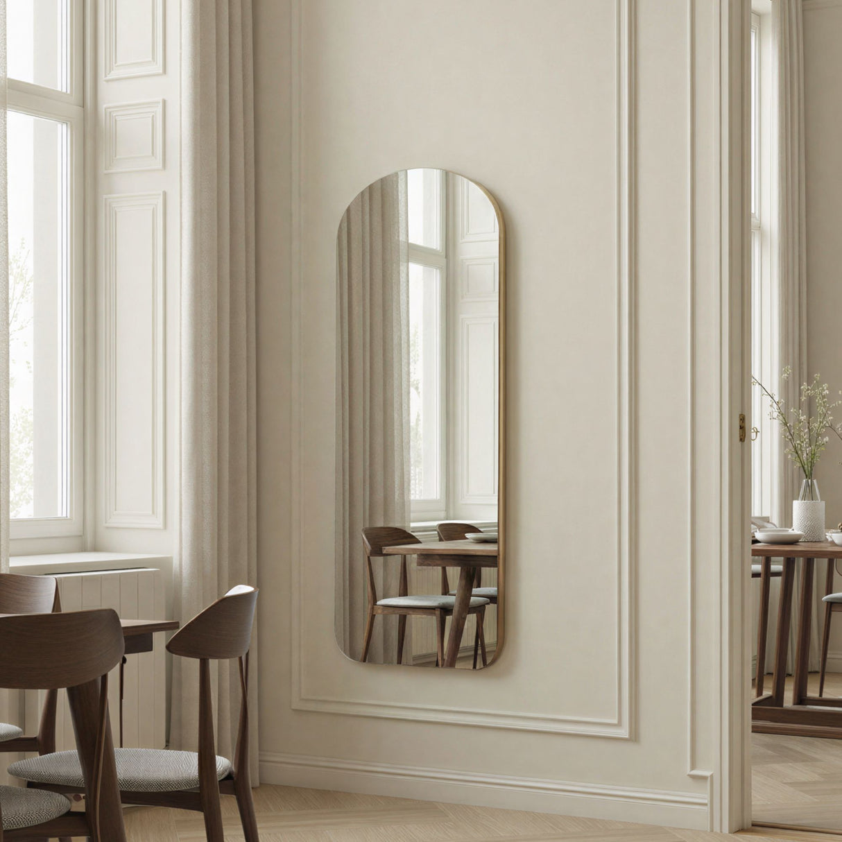Elegant interior with a tall mirror on a wall, wooden chairs, and a dining table.