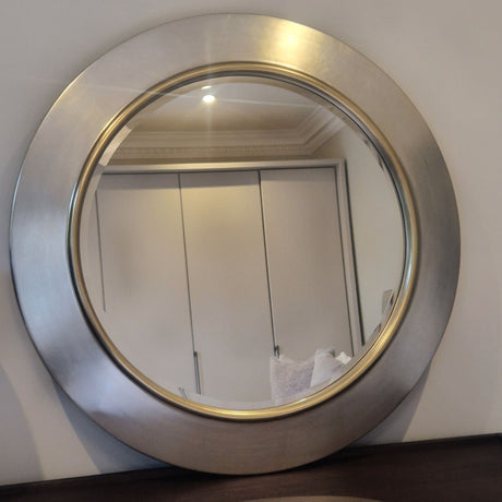 Round mirror with a metallic frame on a wall