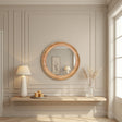 Round wooden mirror on a wall with a lamp and decorative items below.