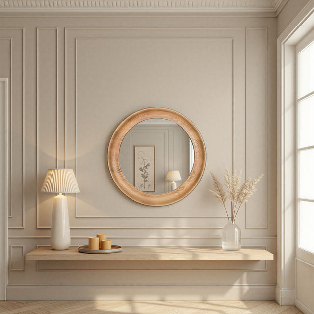Round wooden mirror on a wall with a lamp and decorative items below.