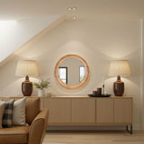 Modern living room with wooden sideboard, round mirror, and lamps.