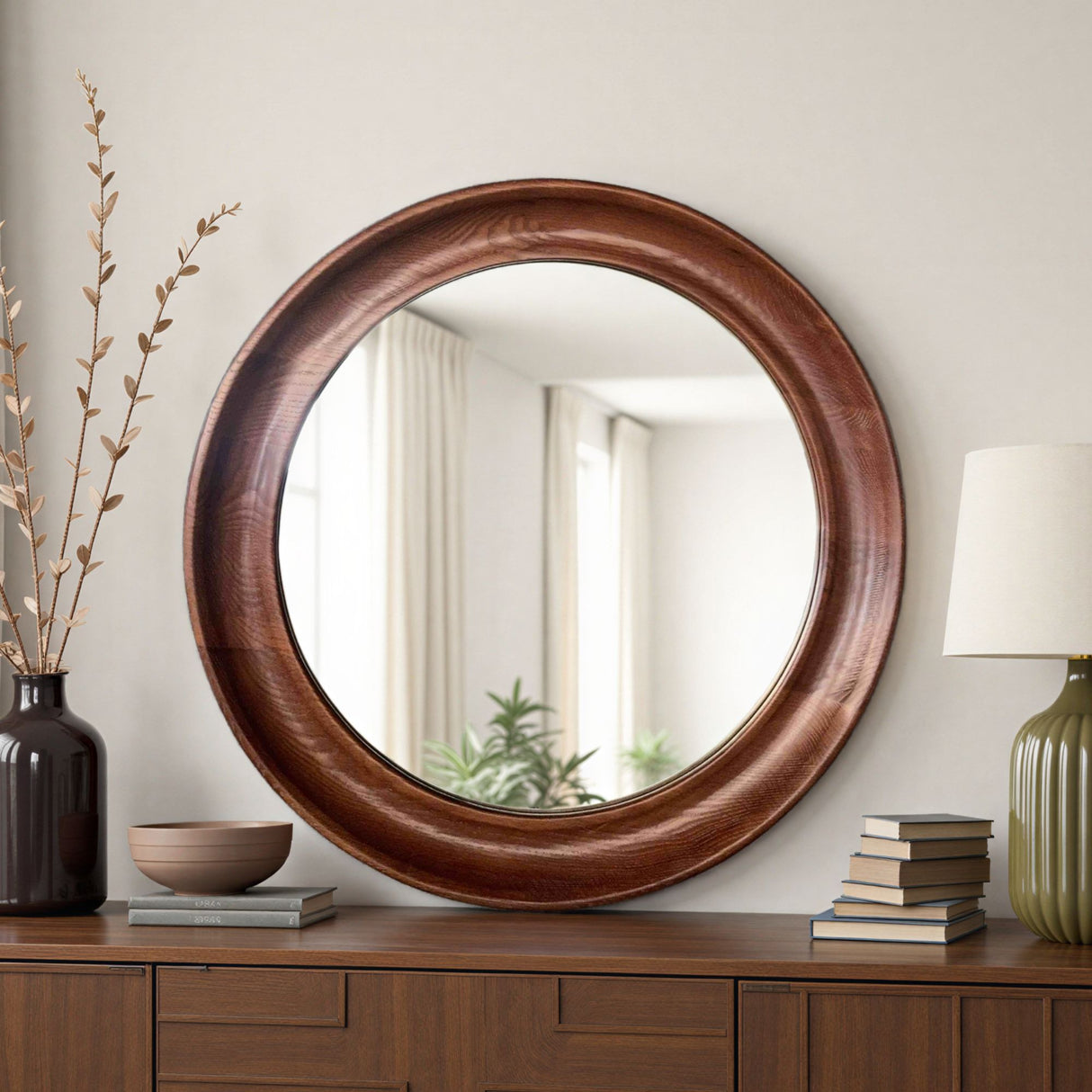 Round wooden mirror on a wooden dresser with decorative items.