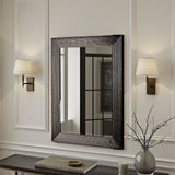 Decorative mirror with wavy frame on a wall with two lamps and a vase.