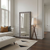 Decorative floor mirror in a stylish living room with a sofa and lamp.