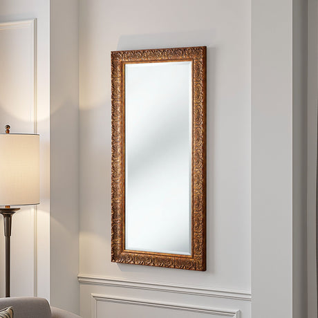 Decorative wall mirror with ornate gold frame on a light gray wall.
