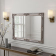 Decorative mirror with ornate frame on a wall above a console table.