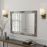 Decorative mirror with ornate frame on a wall above a console table.