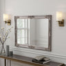 Decorative mirror with ornate frame on a wall above a console table.