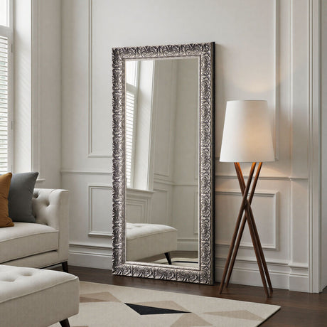 Decorative floor mirror with ornate frame in a living room setting.