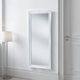 White framed mirror on a white wall with a floor lamp to the left.