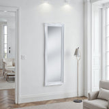 Modern interior with a long rectangular mirror on a white wall, a floor lamp, and a chair.
