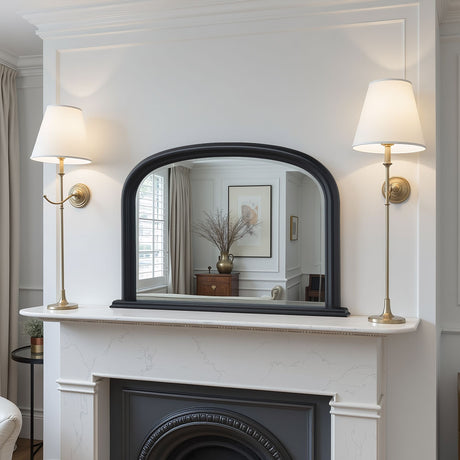 Decorative mirror on a fireplace mantel with wall lamps on either side.