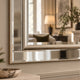 A large rectangular wall mirror with a polished silver frame and beveled edges, mounted on a beige wall in a styled interior setting.