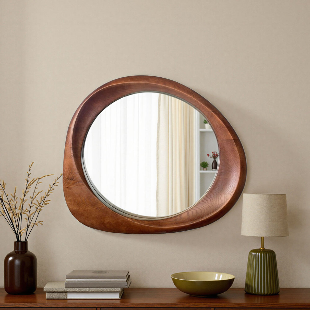 Round wooden mirror on a wall with decor items below