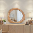 Round wooden mirror on a wooden cabinet with lamps and decor items.