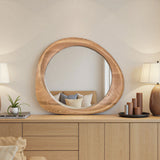 Round wooden mirror on a wooden dresser with decor items in a room.