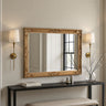 Decorative gold-framed mirror above a console table with wall lights and a vase.