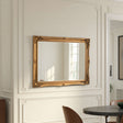 Gold-framed mirror on a wall with decorative molding