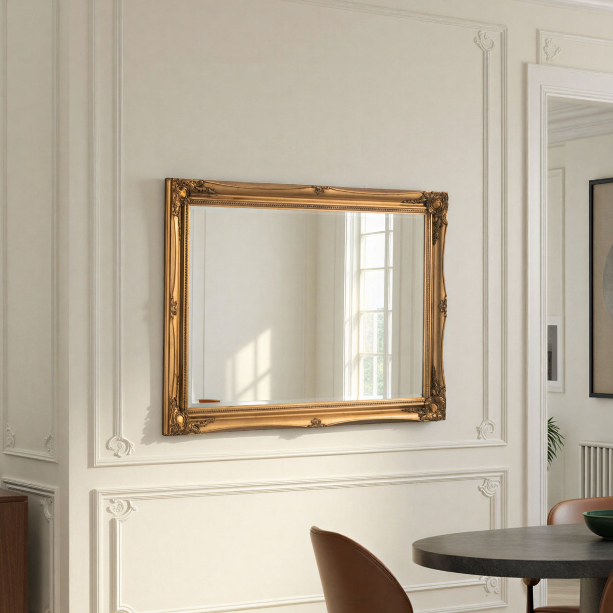 Gold-framed mirror on a wall with decorative molding