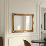 Gold-framed mirror on a wall with decorative molding