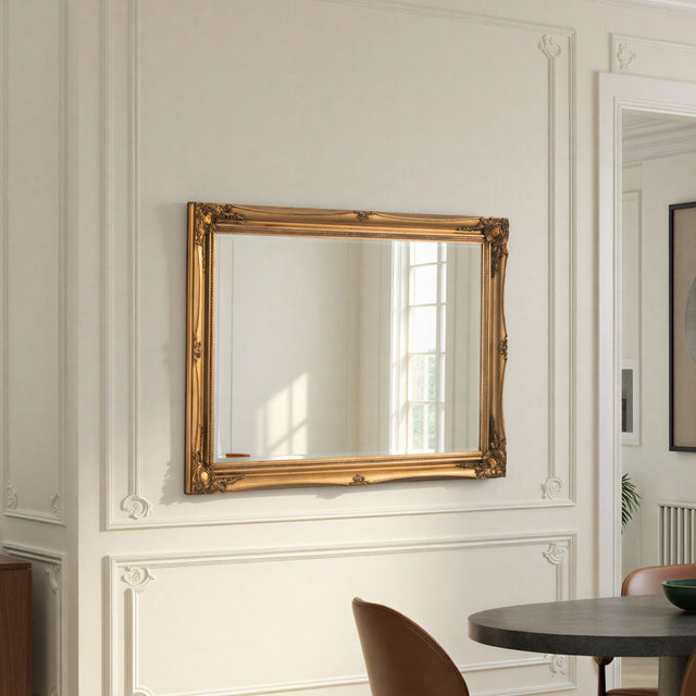 Gold-framed mirror on a wall with decorative molding