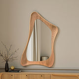 Wooden mirror with wavy frame on a beige wall