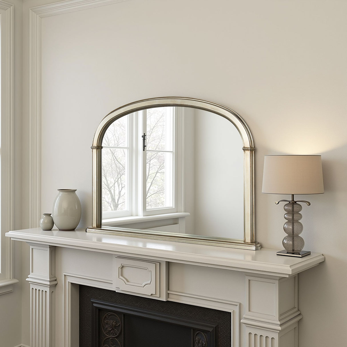 Decorative mirror above a fireplace with a lamp and vases on the mantel.