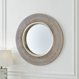 Round decorative mirror with a textured frame on a white wall.