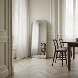 Dining room with a large mirror on the wall, wooden table, and chairs.