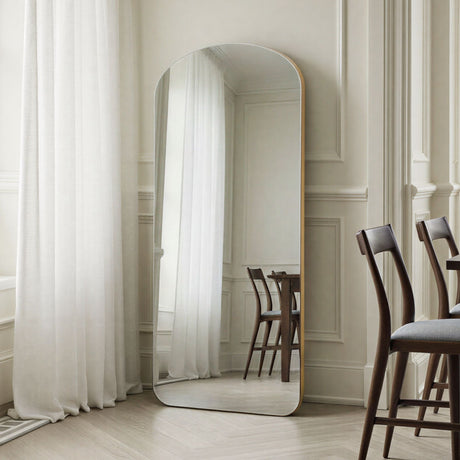 Large floor mirror in a room with white curtains and wooden chairs.