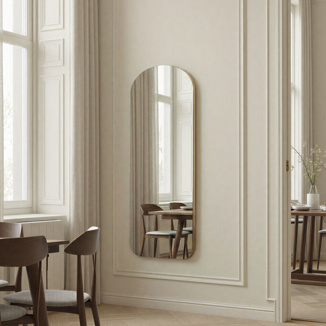 Elegant interior with a tall mirror on a wall, wooden chairs, and a dining table.