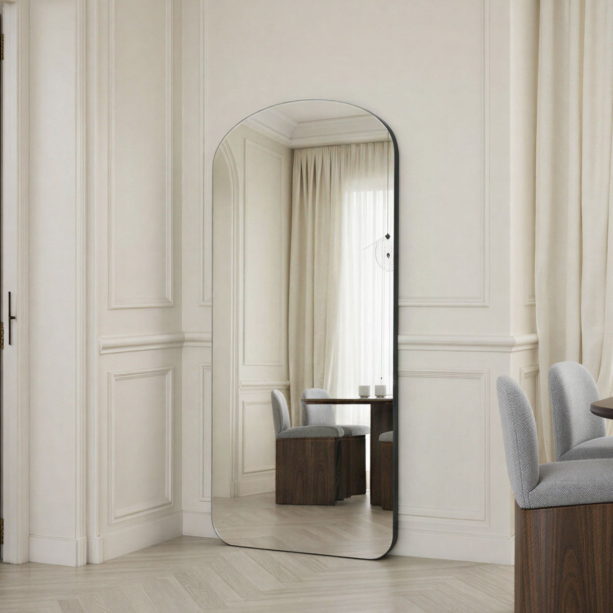 Large floor mirror in a room with white walls and furniture.